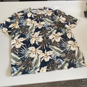 T-shirt  - Blommig t-shirt. Oanvänd. Prislappen kvar. Stl M 