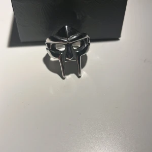 MF DOOM ring - Tja! Säljer denna MF DOOM ring då den inte passar mig👽 Den är i storlek US 11 och är köpt från Seams🔥Den är aldrig använd och är skitsnygg🐉