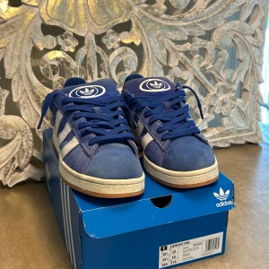 Adidas Campus 00s - Hej! Säljer nu mina Adidas Campus 00s eftersom att den har blivit för små.  Köpte dem förra sommaren och använde dem några gånger innan jag kände att dem var för små. Blåa och vita snören följer med. Fraktkostnaden är ej med i priset. Storlek 44 2/3 