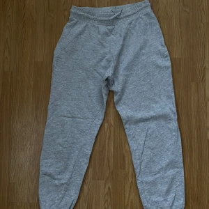 Gråa mjukisbyxor  - Gråa mjukisbyxor från Gina Tricot, silvrig detalj vid knytningen. Inga fickor på dem, säljes pga de är för stora för mig! Fint skick! 