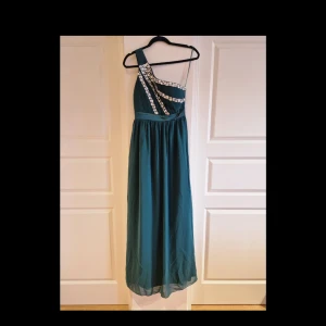 Klänning  - Fin mörkgrön one shoulder aftonklänning med fina dekorativa stenar på överdelen. Använd 1 gång.