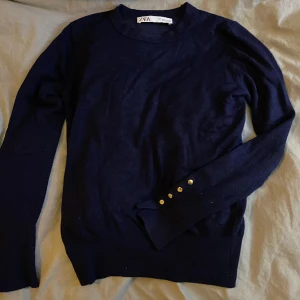 Zara tröja - Mörkblå tröja från Zara med guldiga knappar vid ärmarna. Den är i väldigt bra skick, som ny. Storlek S men passar även XS. Säljer den pga att den ej kommer till användning. Köpt för 329kr, mitt pris är 160kr.