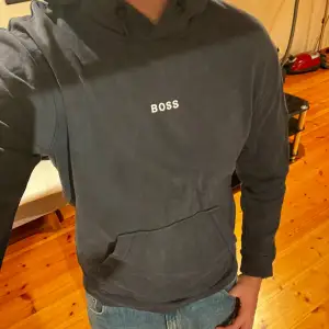 En stilren mörkblå Hugo Boss hoodie  Köpt på Macy’s i San Francisco 2021 för 1700kr  Orginal boss påse följer med   Använd men i gott skick 
