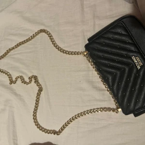 Victoria secret väska  - En svart perfekt liten väska, använt sparsamt, i ett bra skick. Bra kvalite, bandet/ kjedjan går att ha som lång eller kort. Magnet spänne för att stänga. 