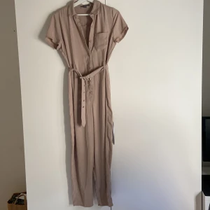 Byxdress  - Fin byxdress i hyfsat tunt tyg. Knappar på framsidan och ett bälte som dras åt i midjan. Lite liten i storleken men passar storlek 36