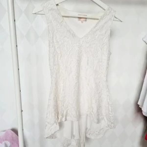 Spetslinne strl XS/S - Strl 10, passar strl XS/S. Spetslinne från Chica London. Längre bak. Ett hål igenom spetsen fram. Lite småskavanker på spetsen i samma område. Inget som stör. Svag färgskiftning i armhålor och invändigt bak. 100% polyester.