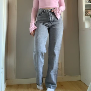 Grå Jeans  - Grå högmidjade jeans ifrån Bikbok. Knappgylf, raka vida ben. Varsamt använda. Köpta för 699 kr. midja:64,5 cm Höfter: 88,5 cm Innerben: 79 cm🤍