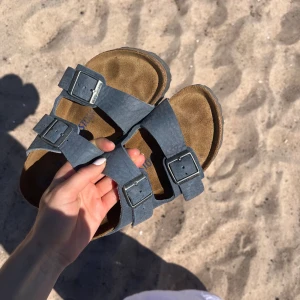 Birkenstock Arizona soft footbed - Birkenstock Arizona i färgen Dusty blue med den smalare passformen. Endast använda under en semestervecka. Stora i storleken🤍Nypris 1370kr Några extra hål gjorda med hålslagare så man kan spänna tajtare!