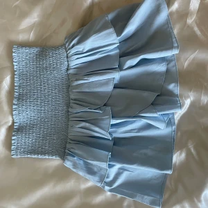 Neo Noir kjol - Säljer denna jättefina ljusblåa volangkjolen från neo noir då jag har en som används mer i en annan färg. Endast använd några gånger förra sommaren så i princip nyskick. Står inte storlek men är ganska säker på att den är i Xs men passar nos S också.