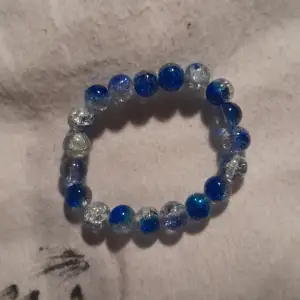 Ett litet armband med blåa och vita pärlor.
