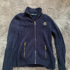 Ralph lauren full zip - Säljer en otroligt fin Ralph lauren cabble nit full zip i mörkblå färg med guldfärgade dragkedjor🤩  Kontakta ifall ni har frågor🤝 
