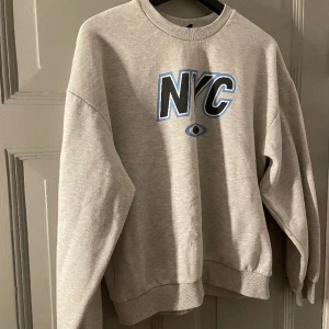 Grå sweetshirt  - Fin grå sweetshirt med blå, vit och svart text på bröstet . Väll använd men inget jag skulle påstå syns. Passar även på folk med storlek m.