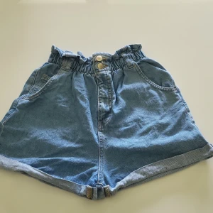 Blå jeansshorts från LAB Industries - Supersköna blåa jeansshorts från LAB Industries i storlek 170, med hög elastisk midja och två knappar framtill. Shortsen har två framfickor och två bakfickor. Säljer då de är för små. (Pris kan diskuteras)