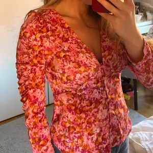 Blus i rosa lila orange, figursydd med knappar fram till