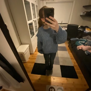 Blå stickad tröja - Blå lite flätstickad tröja med volanger vid armarna. Köpt från lindex. Kontakta mig om frågor eller intresse