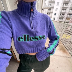 Ellesse, croppad lila tröja, 42/M 🦄 - Croppad stickad tröja, Ellesse, storlek eu42, passar mig som jag s/m upptill, i bomull, köpt secondhand. Lila med svarta och turkosa/gröna ränder 💜🗽