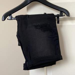 Ett par svarta snygga shorts med fake slitningar både i fram och bak. Dessa är helt oanvända och lappen sitter kvar.