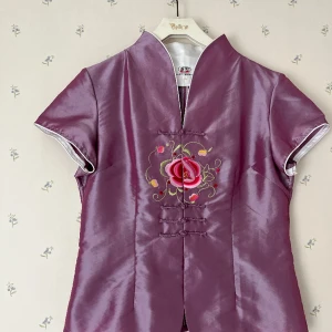 Fin kinesisk sidenblus - Använd ett fåtal gånger. Små fläckar fram på höger axel, se bild. Liten i storleken, mer som L. Bystvidd ca 100 cm. Skickar gärna fler bilder!