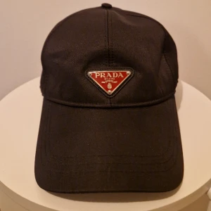 Prada keps *HELT NY!* - Helt ny Prada keps av siden material. Mycket mjuk stilig och glansig. Helt oanvänd.   Kan mötas i Stockholm eller frakta via Plick!