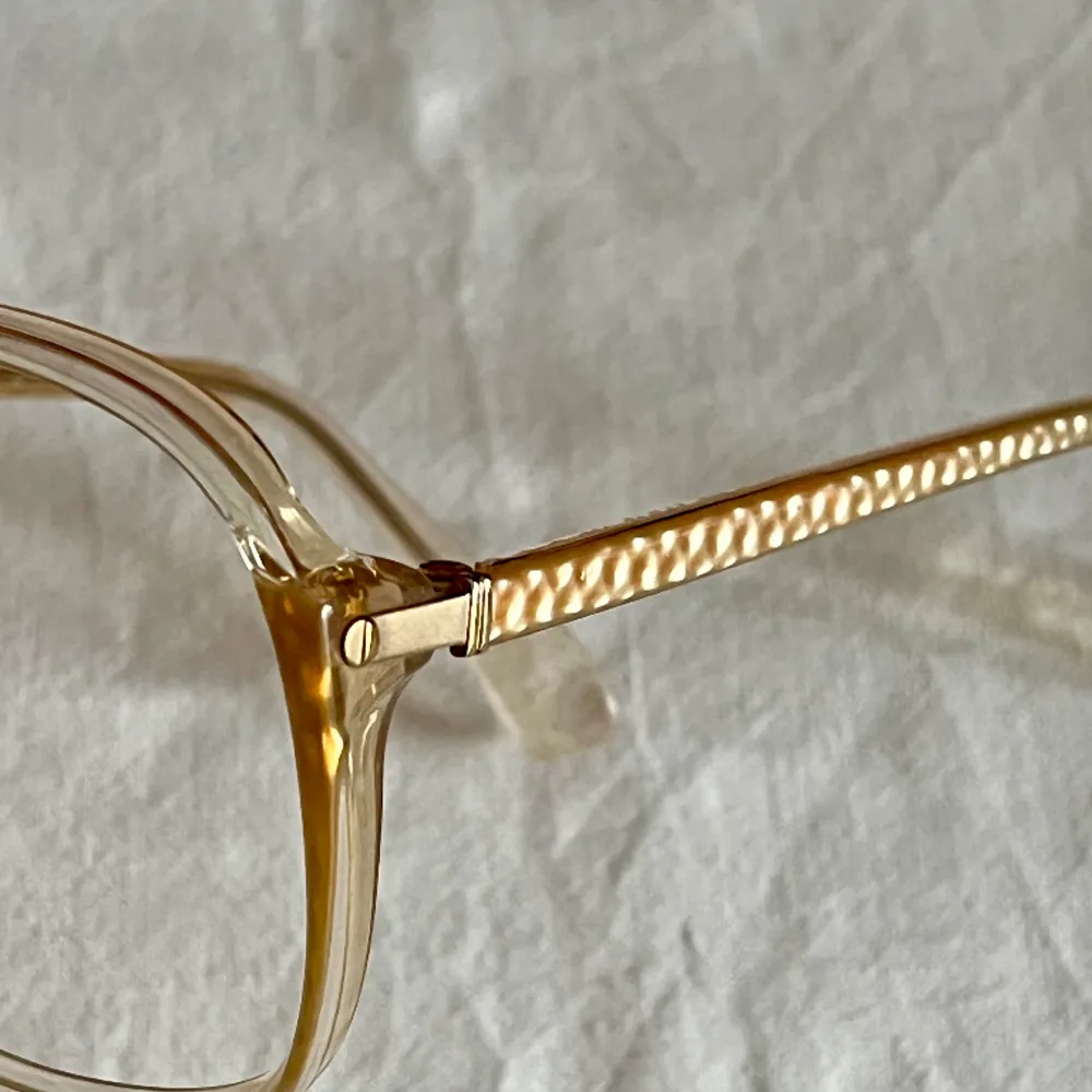 Vintage glasögonbåge från 80 talet  Kommer från en nedlagd Optikbutik, aldrig använd.  Hela bågens bredd 130 mm Glasets storlek, bredd 55 mm, djup 50 mm. Accessoarer.
