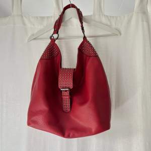 Sjukt snygg rymlig röd väska med nitar. Axelband medföljer. Bredd: ca 43 cm. Höjd: ca 34 cm. Djup: 16 cm. Inga defekter 💕
