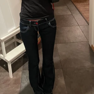 Lågmidjade jeans  - Lågmidjade bootcut jeans, rätt stretchiga material, midja 36 tvärs över (de är väldigt lågmidjade) innerbennslängden ca 85cm💕 de har röda detaljer och vit stitching