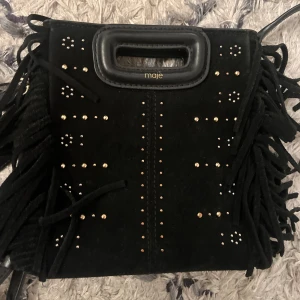Maje väska  - Svart maje väska i mocka med pärlor som detaljer på ena sidan, den har en vatten skada på baksidan men märks inte jätte mycket! Köpt på maje affären i Stockholm för ca 2 år sedan för 2700kr💕dustbag och två axelband följer med! Skriv för mer frågor! 