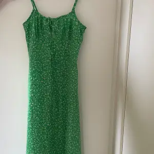 Grön vitblommig klänning (längre än den ser ut på bilden) med rosett framtill och slits. Använd ett fåtal gånger 