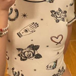 Vit mönstrad crop top - En vit mönstrad tight magtröja. Skulle rekommendera för någon som är stolek xs eller s.  Den är bekväm och är i bra stick. Tyget är stretchingt. 💗(Spegelns reflektion gör så att det ser ut som om den har en fläck men den har inte det)