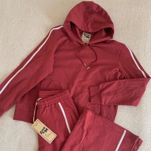 Freedom vinröda mjukiskläder - Supersnygga vinröda mjukiskläder med vita streck på sidorna från märket Freedom. Nya med tags kvar. Byxorna är extremt vida och går att spänna åt på insidan med snöre. Tröjan är oversize. Storlek M i båda delar.