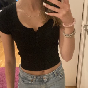 T-Shirt  - Svart t-shirt med knappar och randigt material 