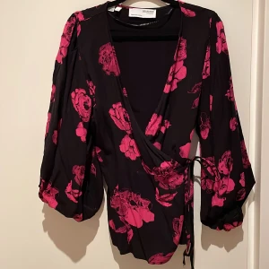 Snygg omlott blus från Selected med cerise blommor på. - Omlottblus som är oanvänd och normal i storlek.