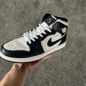 Nike Air Jordan 1 Mid Obsidian - Ett par Nike Air Jordan 1 Mid Obsidian som har använts två gånger i strl EU 43. Har även haft i en shoetree så dem är inte creasade, dvs inga texken på användning. Köpte på soleplus kring 2 papp förra sommaren. 