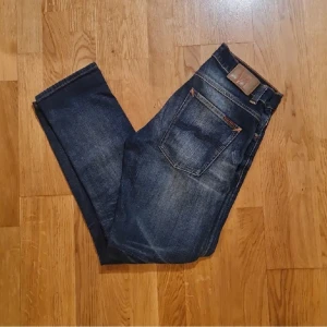 Nudie Jeans - Grim Trim - W31 - L30  - Jeans från Nudie, bra skick enligt bilder och även snygg tvätt med bra "fades". W31 - L30. Sitter bra på mig som är 178 70kg i längden. Nypris 1600 i färgen "dark crispy worn" som inte säljs längre i sortimentet