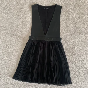 ZARA svart plisserad klänning i skinn imitation  - Otroligt snygg klänning från ZARA med plisserad kjol och överdel i skinn imitation. Använd endast i några timmar. I nyskick, utan anmärkningar. Snygg att styla över en skjorta! 