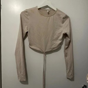 Beige topp Nelly - Säljer denna topp från Nelly som har snören nedtill och som som man snurrar runt magen som en snygg detalj 💗