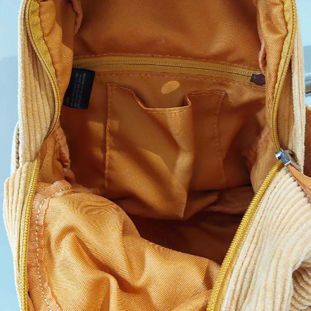 Liten orangebrun ryggsäck men långa axelrämmar. Tillkommer liten skada. Väskor.