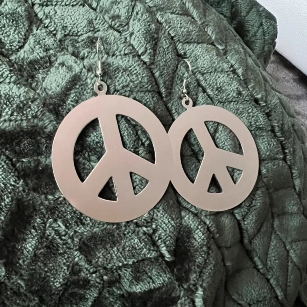 Stora örhängen (ca 5 cm i diameter) med ”peace” symbolen, använda en gång till evenemang men sen blivit liggande i smyckeskrinet och tyvärr blivit lite repigt. Accessoarer.