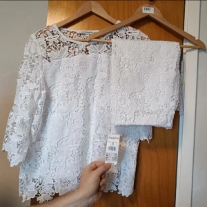 Vit spets set blusa och kjol, stl 42/M, Kappahl. - •Kjol stl M med prislapp kvar, knälång, med undertyg. -Midjan: 85cm -Lång: 58.5cm Blusa med spets, stl 42 ny utan tag, armarna är 3/4 läng,fodrad från bröstet. -Byst: 106cm -Midjan: 110cm -Lång: 61cm -Armlängd: 45cm -Material: 100% polyester på båda