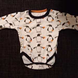 Pingvinbody strl. 56 - Vit body med pingviner i storlek 56 från Pytteliten. I fint begagnat skick, inga hål eller fläckar. Unisex  Tvättad i parfymfritt tvättmedel och utan sköljmedel.