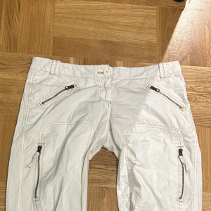 Vita cargobyxor - As coola cargo byxor som jag säljer då de inte passar mig längre💔💔lågmidjade och lite bootcut modell om man drar upp dragkedjorna längst ner 🔥Midjemått: 43cm, Innerbenslängd: 79cm 