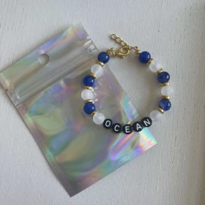 Egengjort pärlarmband  - Egengjort pärlarmband med blåa och vita pärlor. Armbandet har bokstäver som bildar ordet ”ocean”. 