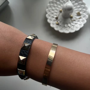 Svart läderarmband med nitar och guldarmband - Ett svart läderarmband med silverfärgade pyramidformade nitar och ett justerbart spänne. köpt från shein och Kappahl. båda för 50kr