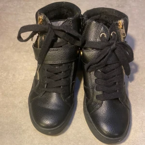 Sneakers- svart - Svarta sneakers med guld detaljer på utsidan. Helt nya oanvänd utan prislapp.