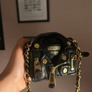 Moschino väska  - En helt oanvänd moschinoväska. Går bara upp i pris varje år! Nypris är 12 000kr nu och nästans slutsåld överallt. Riktigt cool, får plats med läppstift, kort och nycklar. 