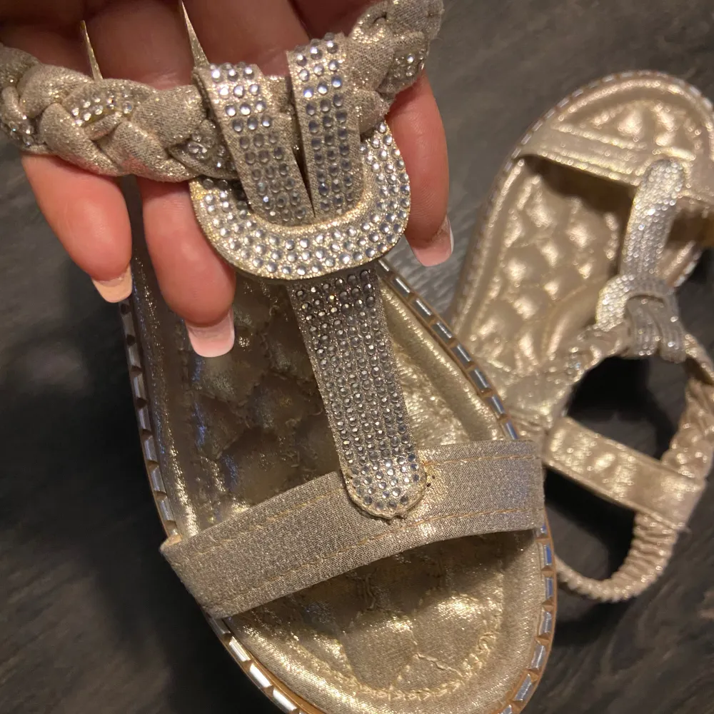 Storlek 40, fint skick  Använd fåtal gånger  Guldiga med silverdetaljer Dessa skor har inget spänne utan som en krinklad kardborrerem runt . Skor.