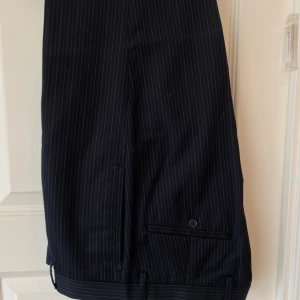 Kostymbyxor- Tiger of Sweden  - Mörka marinblåa kostymbyxor i storlek 48, längd på byxa 97 cm. Ord pris 1200kr.