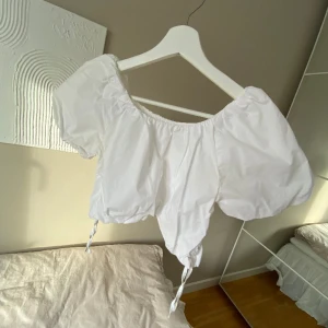 Blus - Vit puffig blus i en lite kortare modell från Zara. Snörning på sidorna som gör att man kan justera längden.