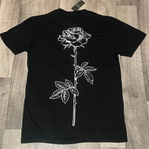 Snygg t-shirt - Säljer en snygg t-shirt från boohooman med ros 🌹 print på baksidan. Aldrig använd, bara testats en gång. Säljs på pga fel storlek. Pris går diskuteras!  Meddela om ni är intresserade eller har frågor så svarar så fort jag kan