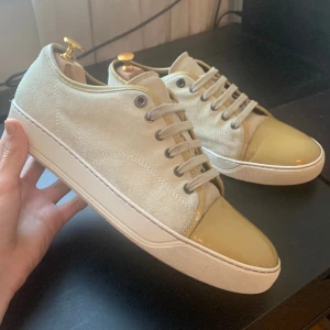 Lanvin skor - Ljusbeigea Lanvins med glans - väldigt bra skick använda fåtal gånger. Nypris ligger runt 4000 vårat pris 1999 kr. Skorna är i storlek UK 9 vilket motsvarar 43. Skorna är lite stora i storleken, borde passa 43.5 /44. Skorna medföljer endast vid köp. 